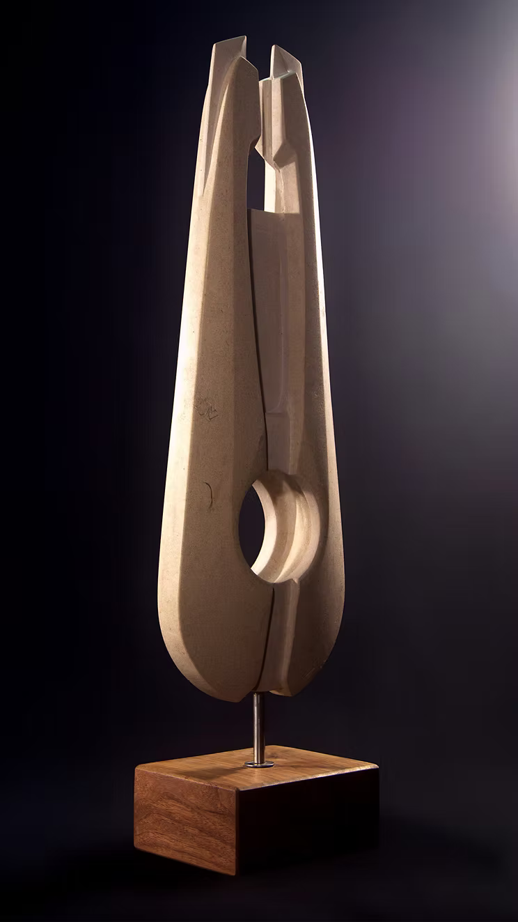 Stone sculpture featuring two tall, curved spires carved from Purbeck Thornback stone, set on a polished black granite base, connected by a narrow central opening with stainless steel elements, displayed against a dark background.