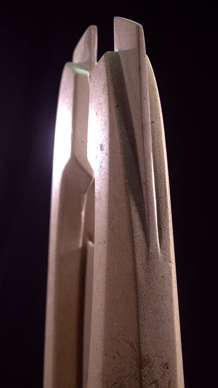 Stone sculpture featuring two tall, curved spires carved from Purbeck Thornback stone, set on a polished black granite base, connected by a narrow central opening with stainless steel elements, displayed against a dark background.
