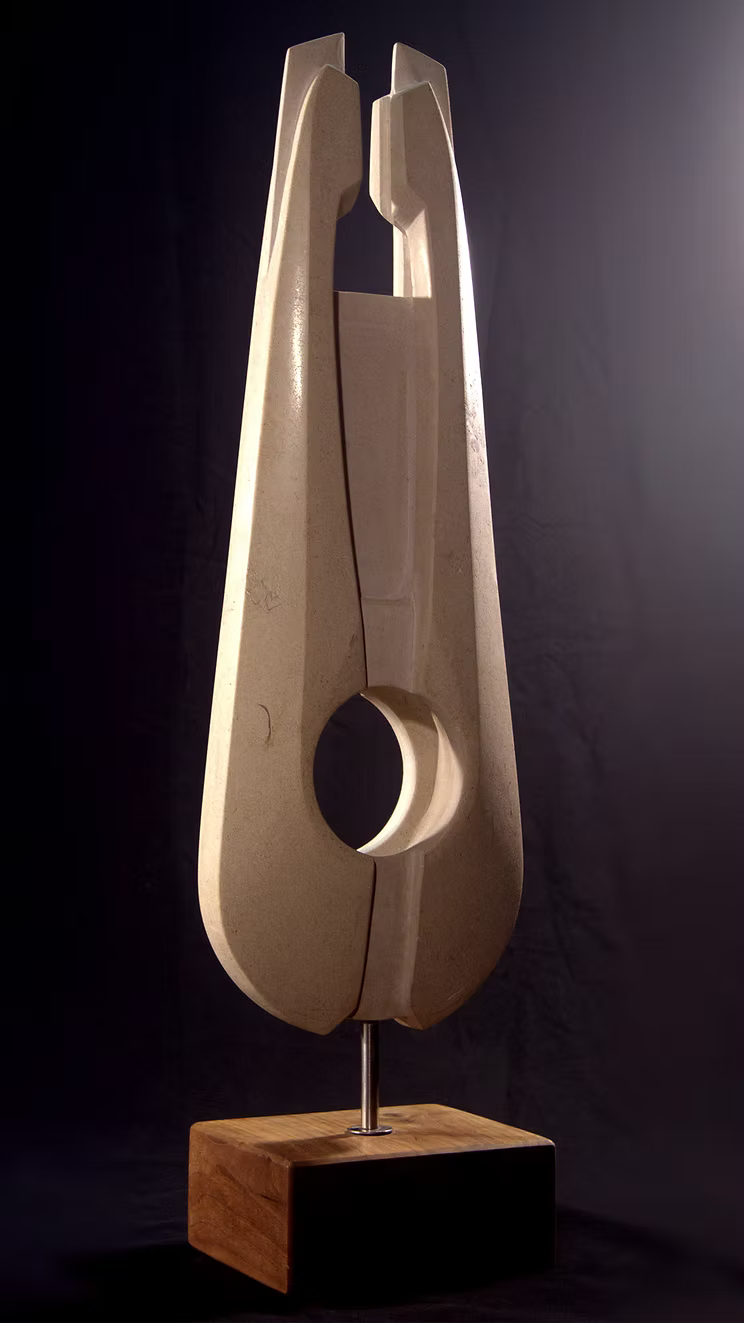 Stone sculpture featuring two tall, curved spires carved from Purbeck Thornback stone, set on a polished black granite base, connected by a narrow central opening with stainless steel elements, displayed against a dark background.