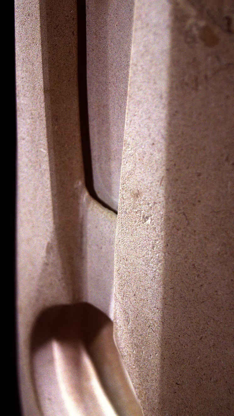 Stone sculpture featuring two tall, curved spires carved from Purbeck Thornback stone, set on a polished black granite base, connected by a narrow central opening with stainless steel elements, displayed against a dark background.