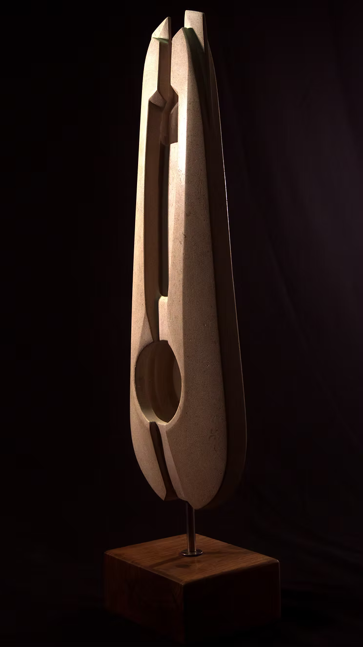 Stone sculpture featuring two tall, curved spires carved from Purbeck Thornback stone, set on a polished black granite base, connected by a narrow central opening with stainless steel elements, displayed against a dark background.