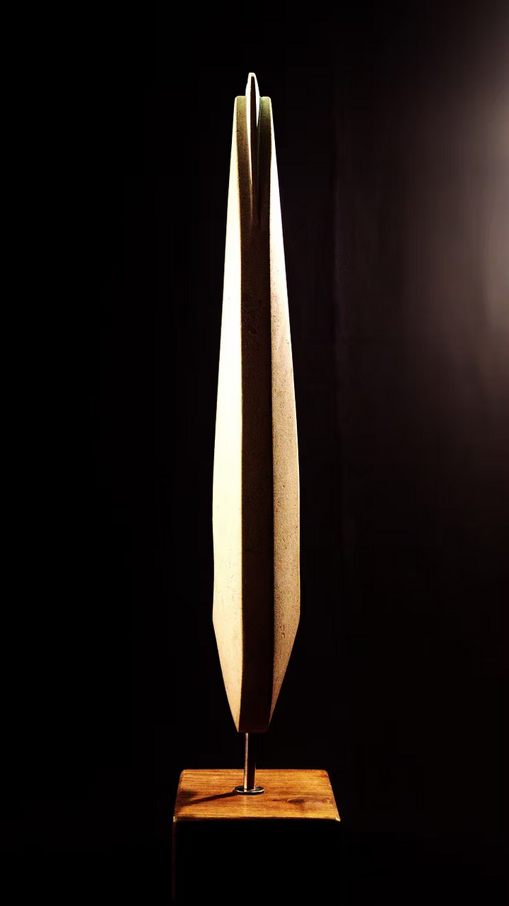 Stone sculpture featuring two tall, curved spires carved from Purbeck Thornback stone, set on a polished black granite base, connected by a narrow central opening with stainless steel elements, displayed against a dark background.