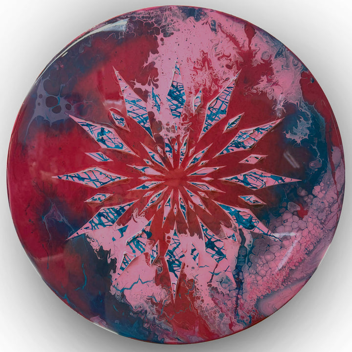 Circular contemporary wall artwork by Mike Philp featuring radiating geometric forms cutting through fluid fields of red, pink and blue. Sharp structure contrasts with organic movement beneath a high-gloss resin surface, creating depth, energy, and controlled expansion.