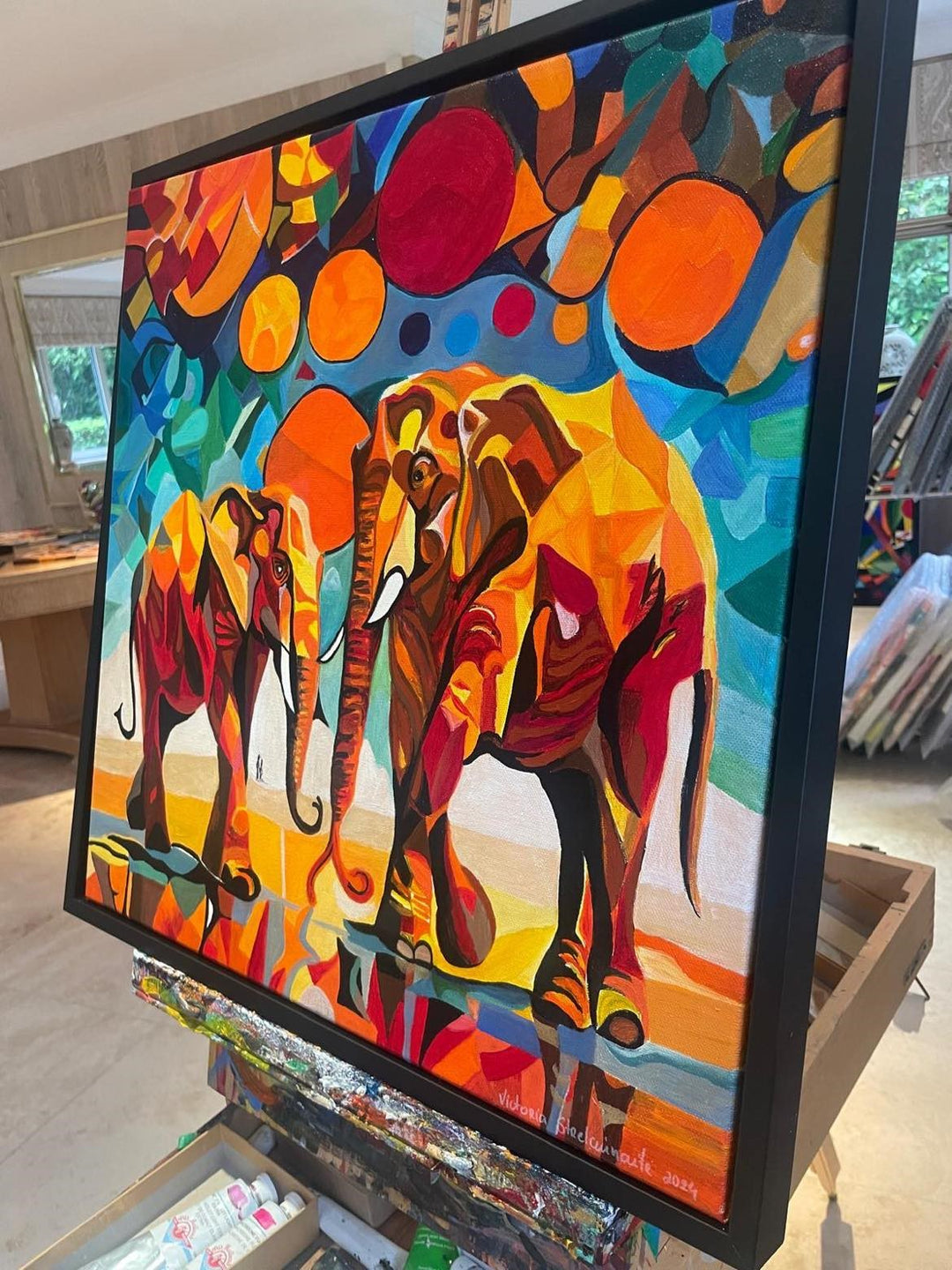 Two abstract elephants in bold, vivid colours with geometric backgrounds and circular sun motifs.

