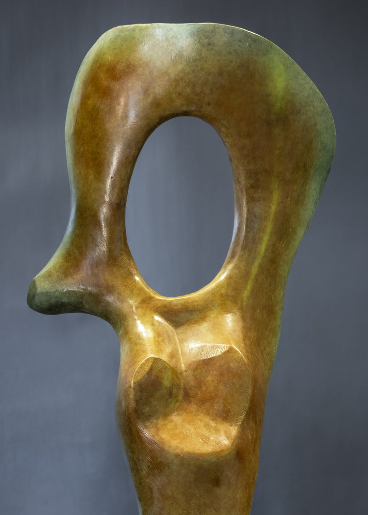 Abstract bronze sculpture of a stylised female torso with flowing curves and a hollowed circular form near the head, displayed in various outdoor and indoor settings. The sculpture has a rich patinated surface with green, gold, and bronze tones.