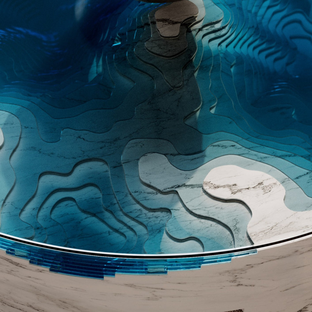 Duffy London Abyss Marble Horizon coffee table in white Carrara marble with layered blue glass, creating a sculptural ocean-depth illusion within a circular form.