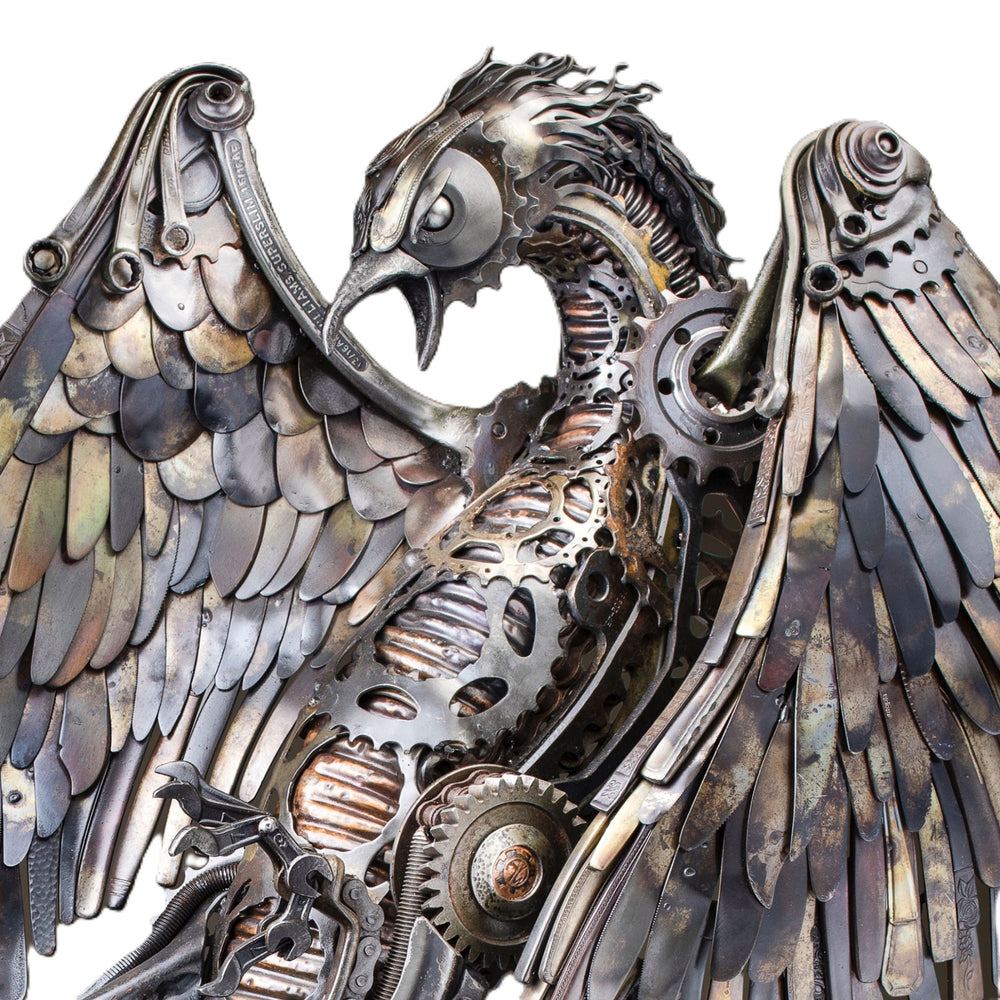 Winged steampunk Phoenix sculpture crafted from reclaimed metal with mechanical detailing and flowing tentacle-like elements.