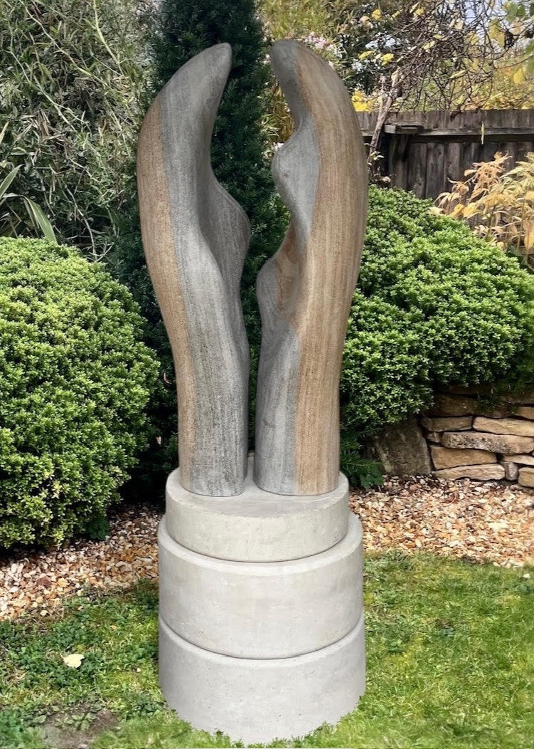 Contemporary stone sculpture titled Almost Touching, carved from Ancaster Weatherbed and set on a Portland stone base. Two elegant vertical forms rise in soft curves, nearly meeting at the centre, symbolising connection and balance within natural harmony.