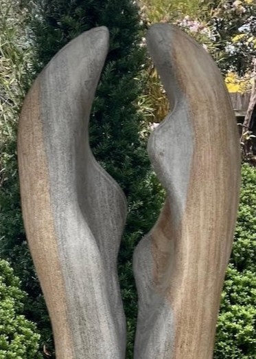 Contemporary stone sculpture titled Almost Touching, carved from Ancaster Weatherbed and set on a Portland stone base. Two elegant vertical forms rise in soft curves, nearly meeting at the centre, symbolising connection and balance within natural harmony.