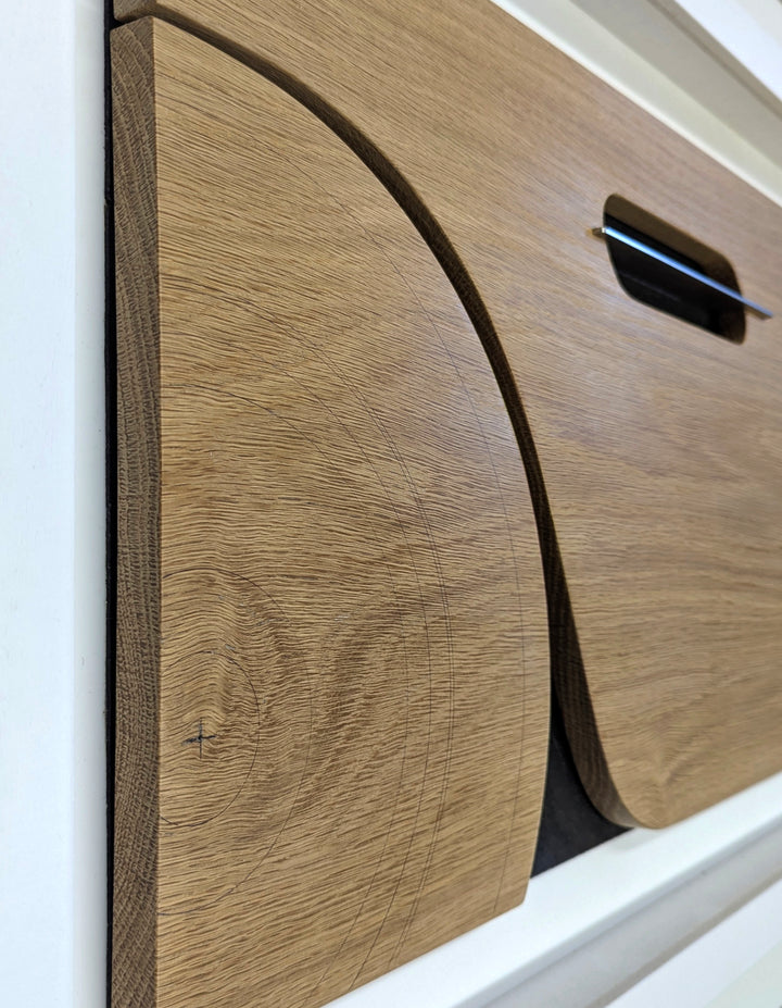 Jonny Ambrose minimalist oak wall sculpture featuring the side profile of an Aston Martin DB5 with carved wheel arch and signature side vent, accented with aluminium detail on a white Corian backdrop.