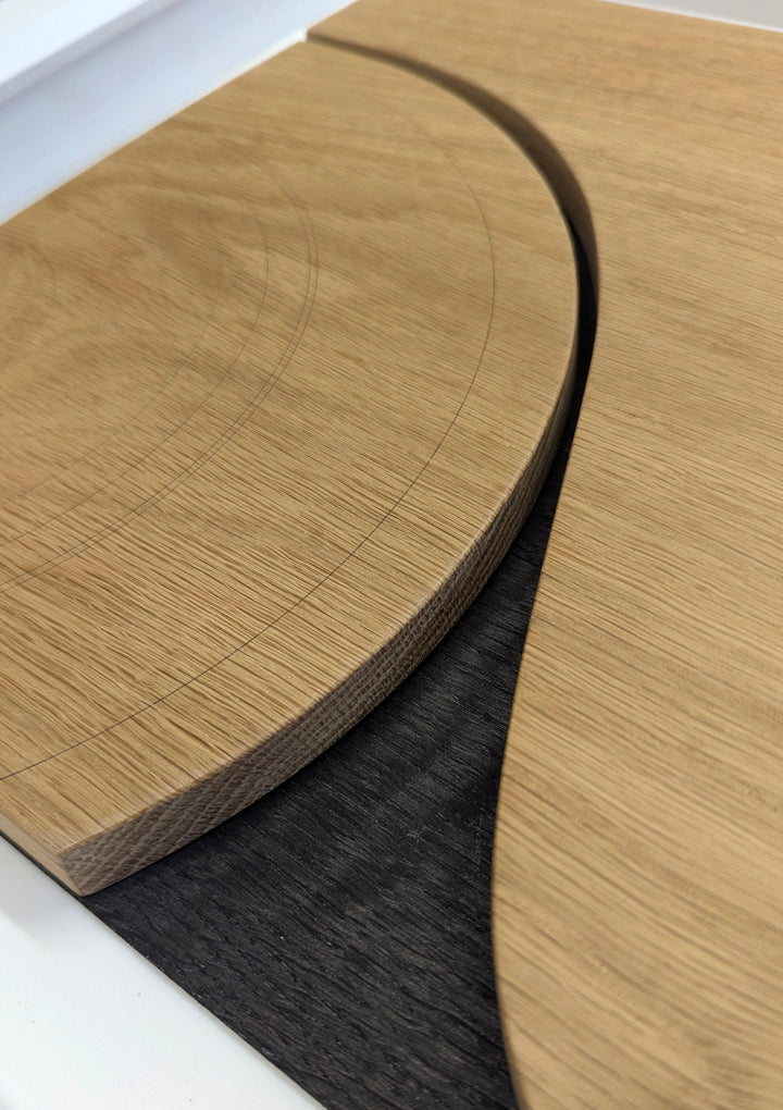 Jonny Ambrose minimalist oak wall sculpture featuring the side profile of an Aston Martin DB5 with carved wheel arch and signature side vent, accented with aluminium detail on a white Corian backdrop.