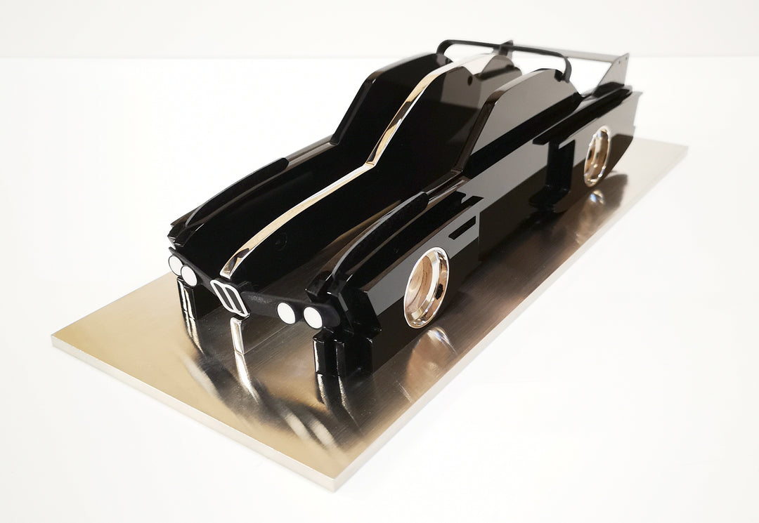 Sculptural model of the 1970s BMW E9 “Batmobile” touring car by Jonny Ambrose — a black, layered acrylic and carbon fibre form with polished aluminium details on a brushed acrylic plinth, capturing its dramatic wings and flared racing silhouette.
