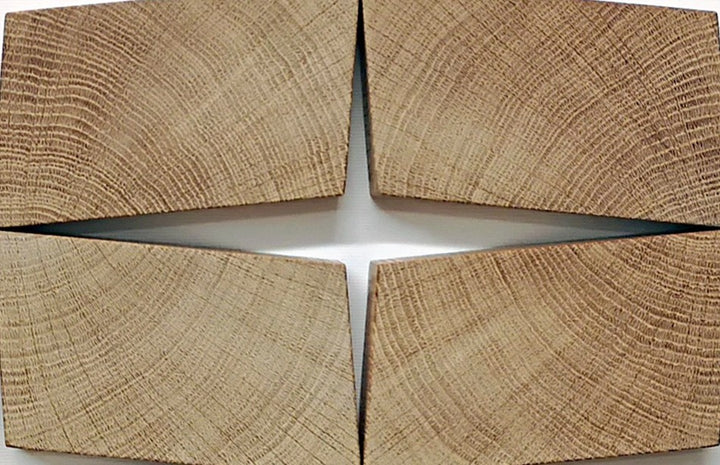 Abstract oak wall sculpture by Jonny Ambrose — twelve angled endgrain oak blocks arranged to shift and expand across a clean white canvas, creating depth, movement, and warm natural texture.