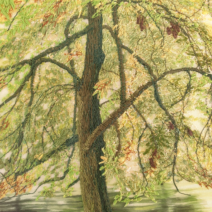 Embroidered woodland scene with moss-covered tree trunks, autumn leaves on the forest floor, and a calm river reflecting soft light.