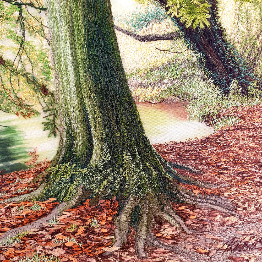 Embroidered woodland scene with moss-covered tree trunks, autumn leaves on the forest floor, and a calm river reflecting soft light.
