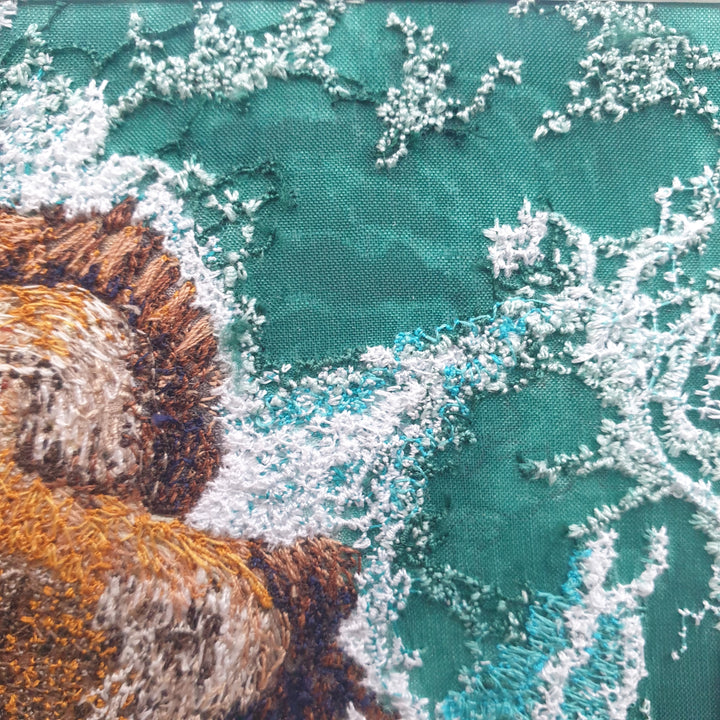 Textile artwork depicting rocky outcrops surrounded by swirling green-blue sea, created with freehand machine embroidery on painted silk.