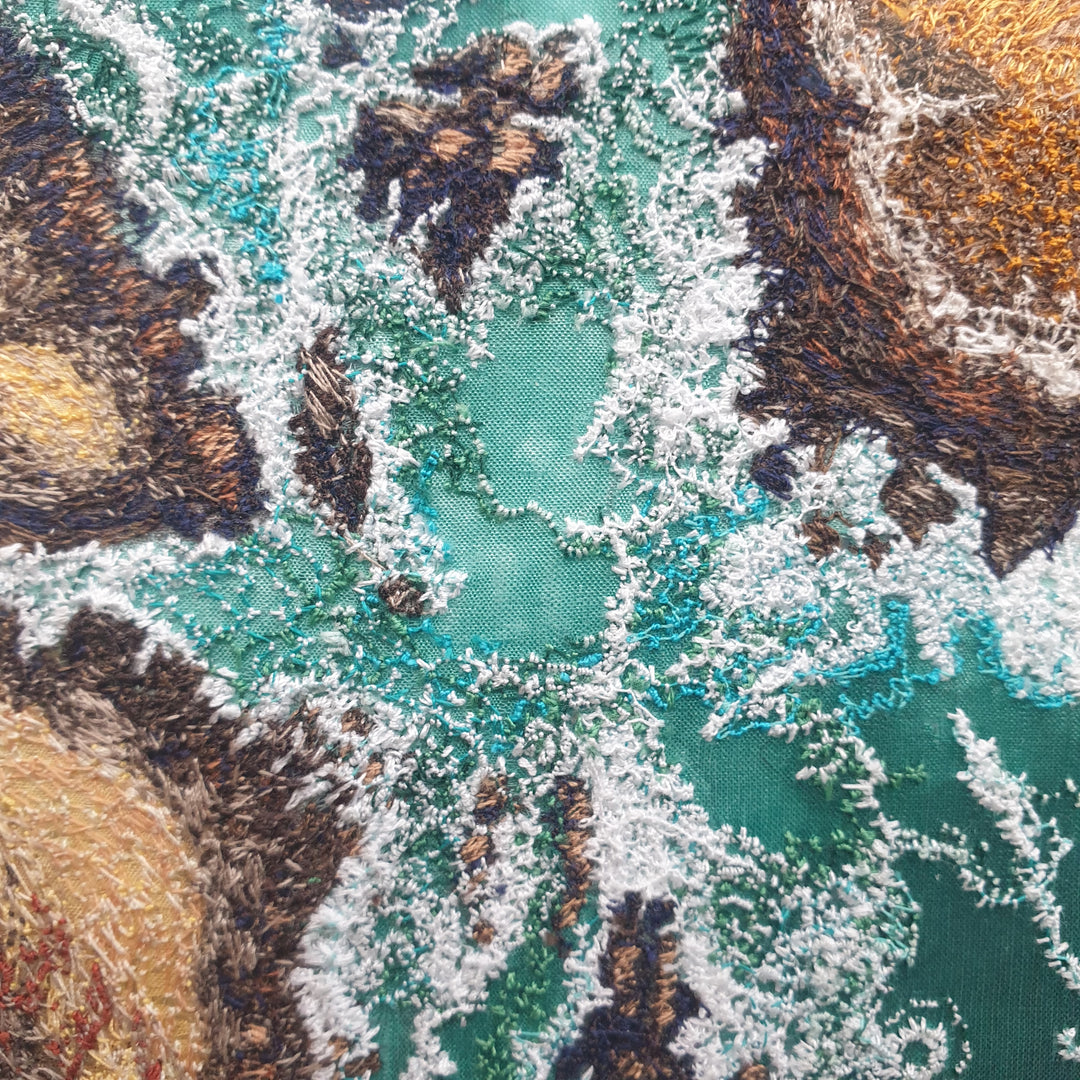 Textile artwork depicting rocky outcrops surrounded by swirling green-blue sea, created with freehand machine embroidery on painted silk.