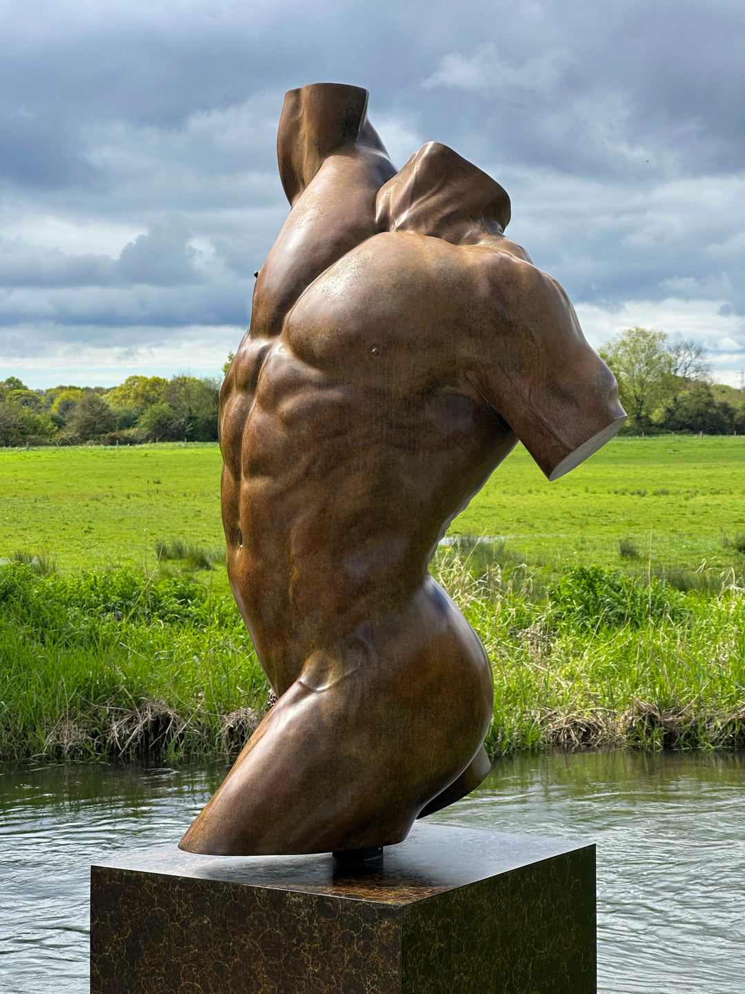 A powerful bronze torso sculpture by Nick Bibby, depicting Apollo with precise classical anatomy, a rich dark-bronze patina, and an upward twisting form displayed on a bronze plinth.