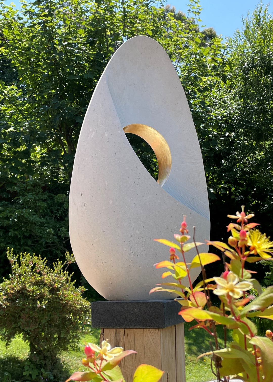 Auric Dawn by Nicola Axe — smooth teardrop-shaped Portland stone sculpture with a precision-cut circular void lined in shimmering gold leaf, set on a mixed oak and granite plinth, minimal yet meditative in form.