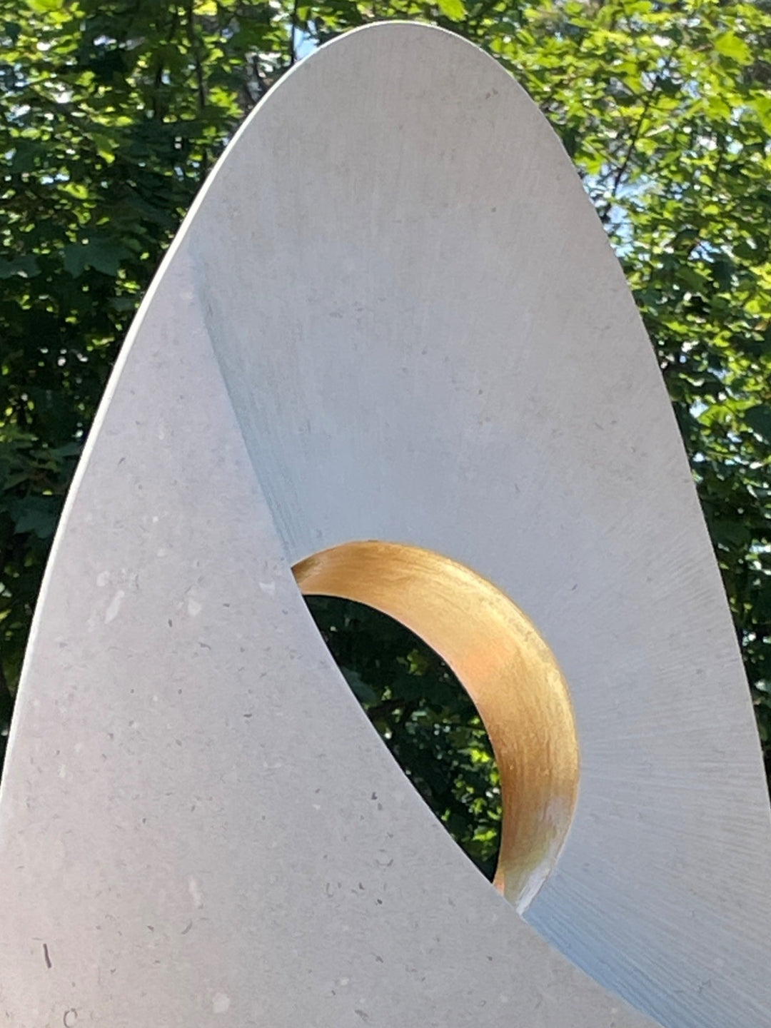 Auric Dawn by Nicola Axe — smooth teardrop-shaped Portland stone sculpture with a precision-cut circular void lined in shimmering gold leaf, set on a mixed oak and granite plinth, minimal yet meditative in form.