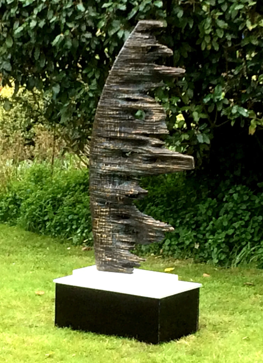 Abstract vertical bronze sculpture with jagged, organic edges, positioned outdoors on a white marble and ceramic base; Edition 1 of 8.