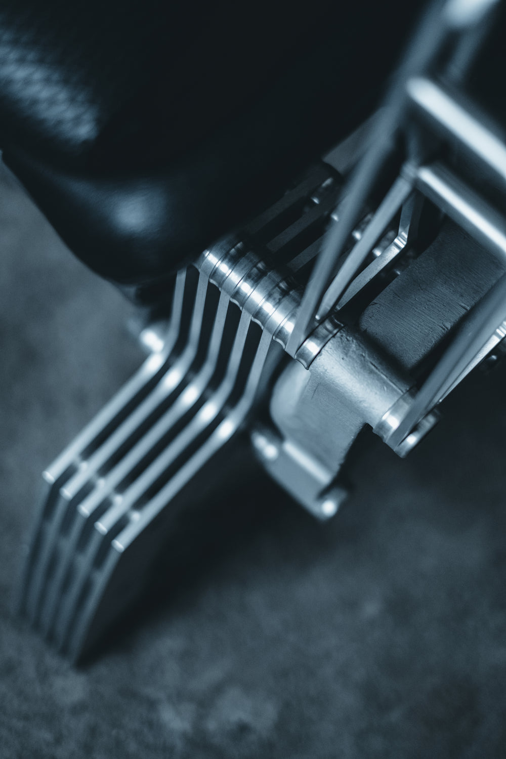 Pair of bespoke chairs handcrafted from original Porsche 914 seats and precision-engineered components, including billet aluminium legs, a modified 914 torsion tube, and hand-shaped walnut armrests, photographed in an industrial garage setting with a classic Porsche in the background.