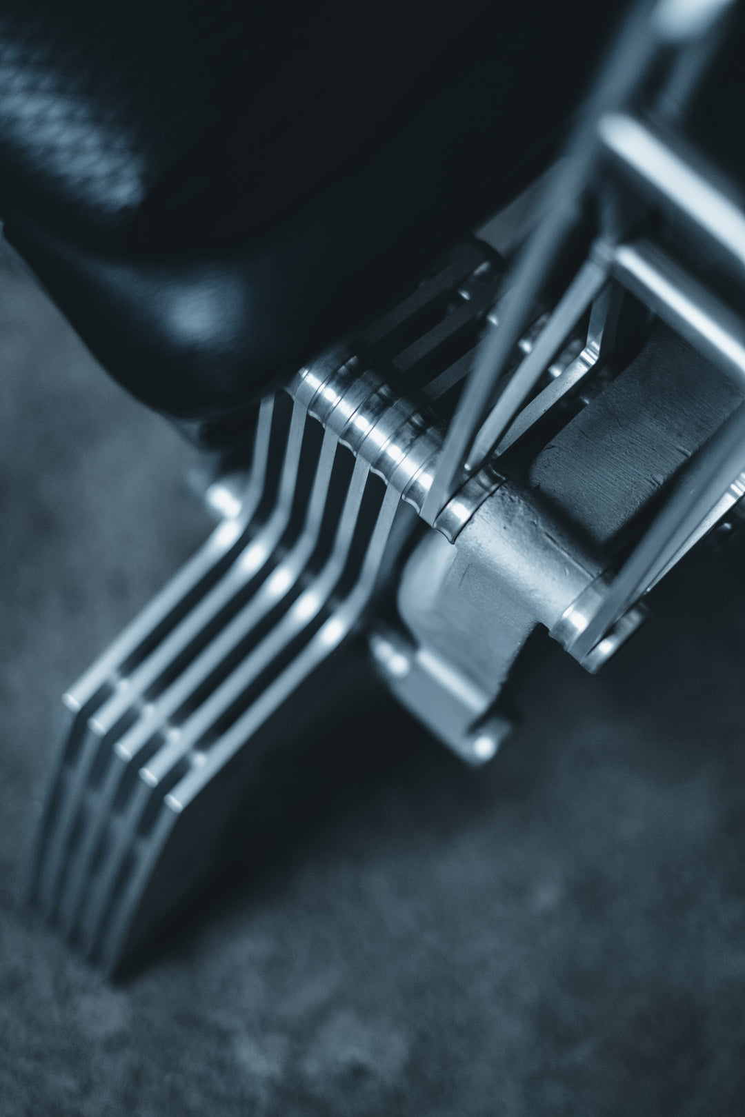 Pair of bespoke chairs handcrafted from original Porsche 914 seats and precision-engineered components, including billet aluminium legs, a modified 914 torsion tube, and hand-shaped walnut armrests, photographed in an industrial garage setting with a classic Porsche in the background.