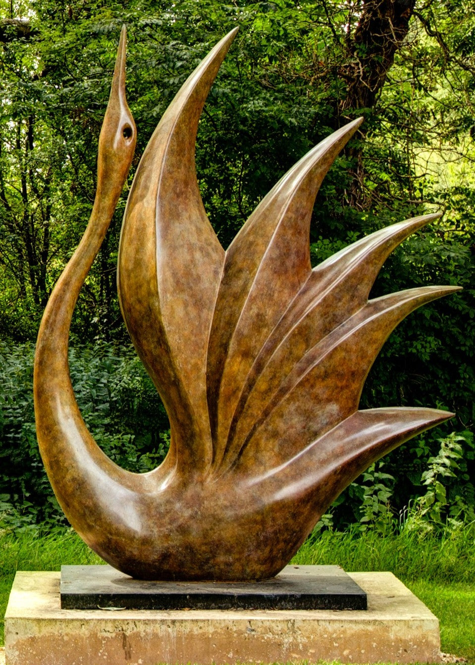 Simon Gudgeon bronze sculpture Bird of Happiness featuring an elegant crane-inspired contemporary bronze form with sweeping curved lines displayed within a landscaped garden setting.