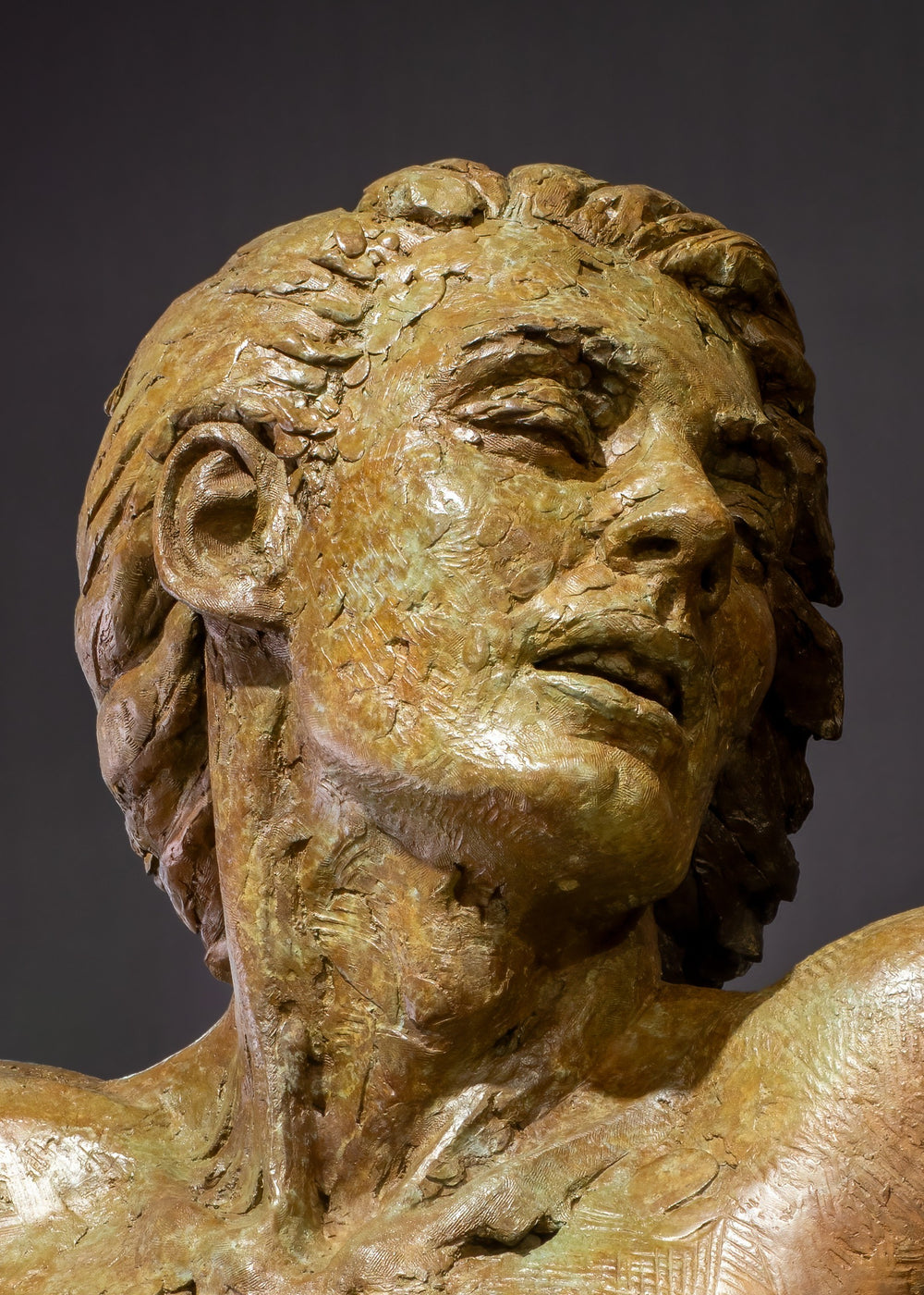 Nicola Godden Bliss Icarus bronze sculpture portraying a stylised human figure rising upward with arms extended and head turned, evoking a moment of release and quiet strength. The elongated form suggests lift and motion while remaining grounded through a solid Corten steel base. The textured bronze surface carries depth and variation, with light catching across its contours to enhance the sense of movement and presence.