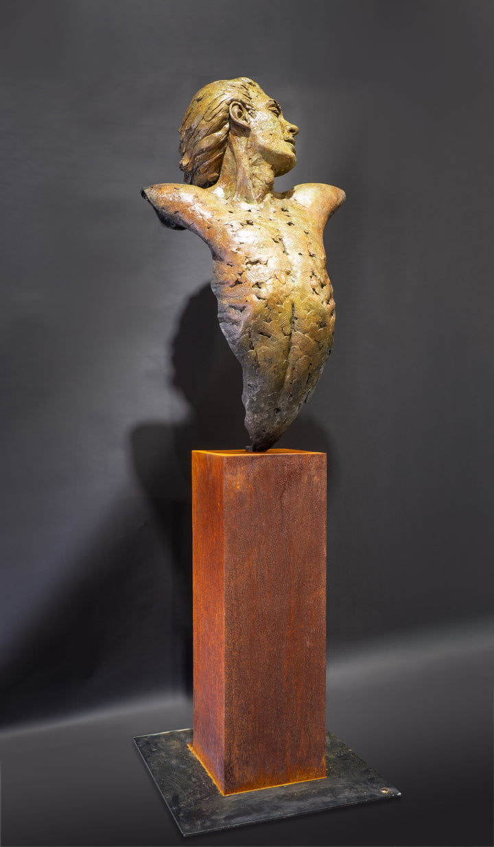 Nicola Godden Bliss Icarus bronze sculpture portraying a stylised human figure rising upward with arms extended and head turned, evoking a moment of release and quiet strength. The elongated form suggests lift and motion while remaining grounded through a solid Corten steel base. The textured bronze surface carries depth and variation, with light catching across its contours to enhance the sense of movement and presence.