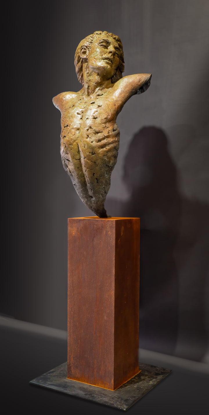 Nicola Godden Bliss Icarus bronze sculpture portraying a stylised human figure rising upward with arms extended and head turned, evoking a moment of release and quiet strength. The elongated form suggests lift and motion while remaining grounded through a solid Corten steel base. The textured bronze surface carries depth and variation, with light catching across its contours to enhance the sense of movement and presence.