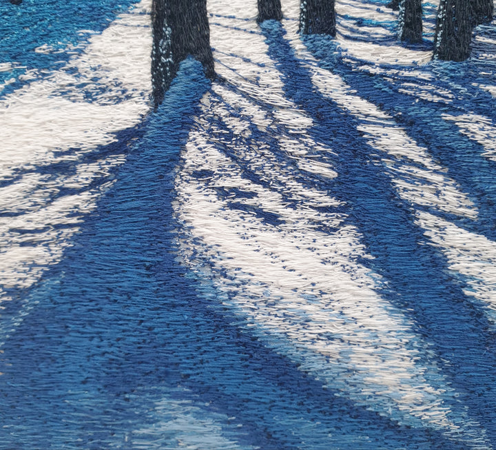 Textile artwork depicting blue winter shadows cast by trees across snow, created with freehand machine embroidery on painted silk.