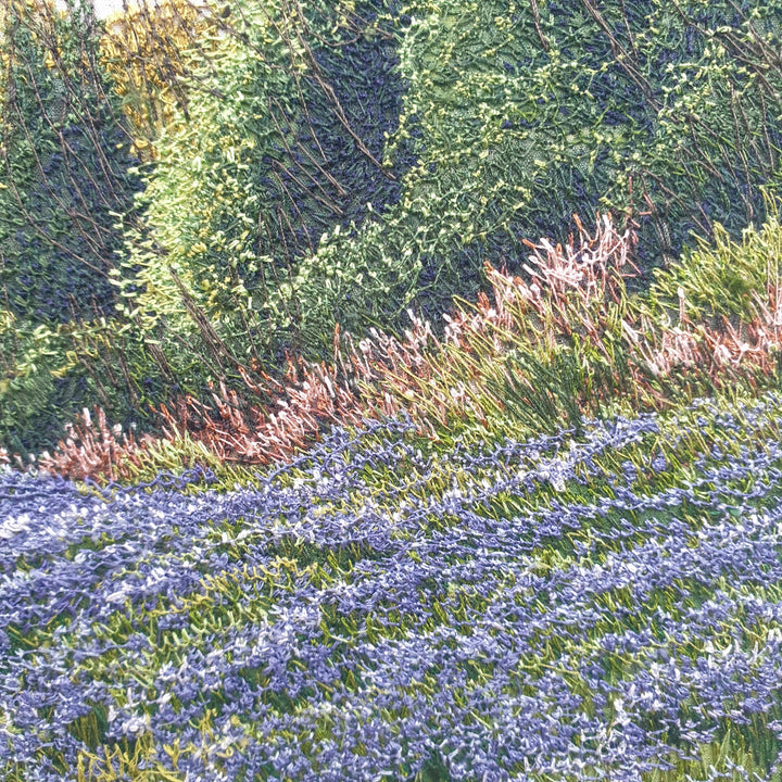 Textile artwork depicting a bluebell-covered landscape with a large oak tree and winding path, created with freehand machine embroidery on painted silk.