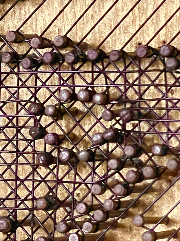 Portrait of David Bowie formed from fine black enamelled copper wire tensioned around thousands of small nails on a gold-toned board, with layered linear wiring defining facial features and hair through tonal contrast, depth and shadow across a textured metallic surface that shifts with light and viewing angle.