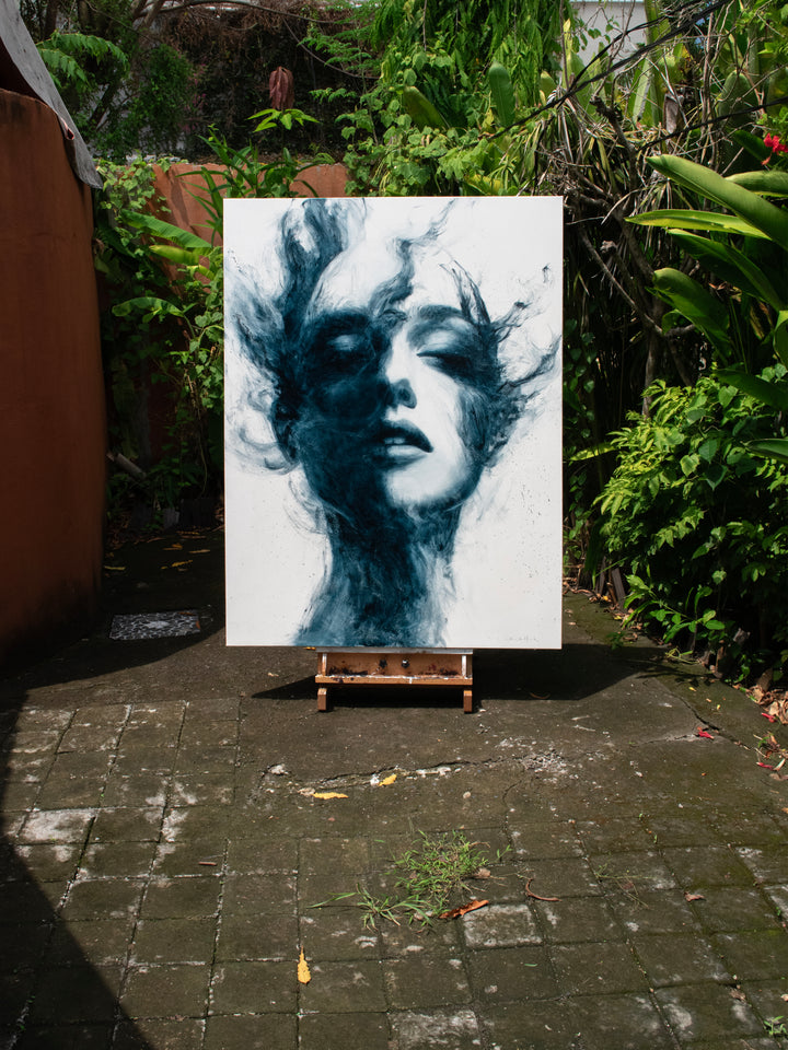 Large oil on canvas painting by Dan Bullock, titled Breathe. A monochrome portrait of a female face with eyes closed, emerging from swirling, smoky brushstrokes in deep teal and black against a pale background, balancing realism and abstraction.