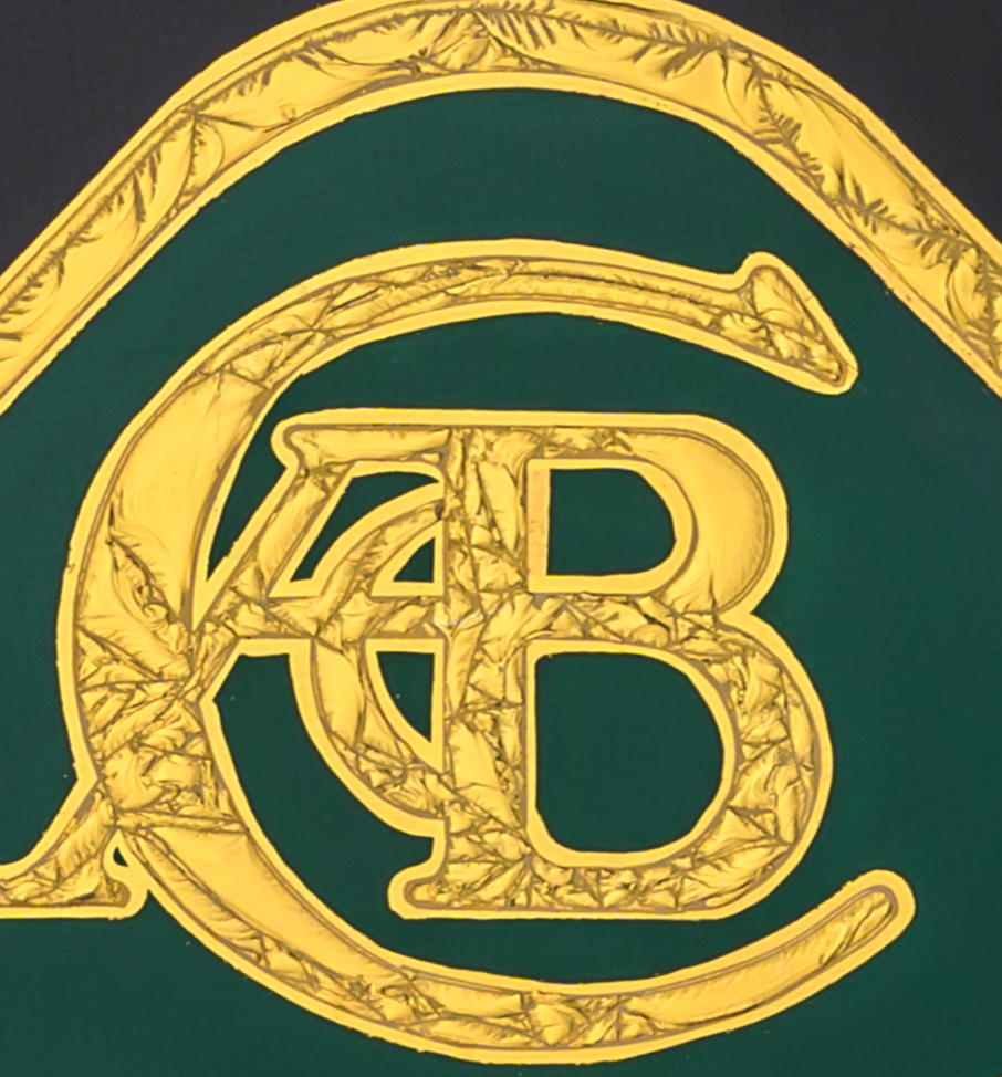 ‘CC Passion’ by Vince Edmunds, a handcrafted automotive artwork celebrating the British Lotus marque, featuring the classic Lotus emblem recreated in 24-carat gold leaf and glue-chipped glass. Intricately textured gold lettering and circular detailing surround the distinctive green Lotus badge against a deep black background, presented in a satin black frame with a fine gold sight line.