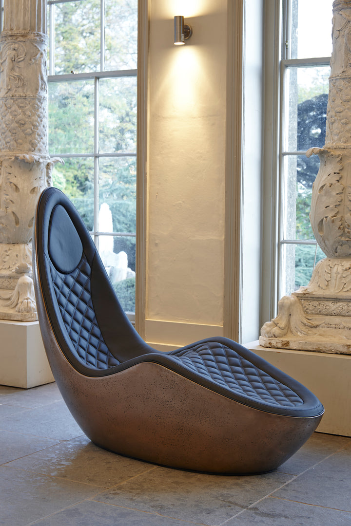 “Caillou Chaise – Leather & Bronze” by Ben Rousseau – a sculptural chaise combining deep navy quilted leather with a liquid bronze base. A handcrafted fusion of strength and sophistication, redefining modern luxury furniture.

