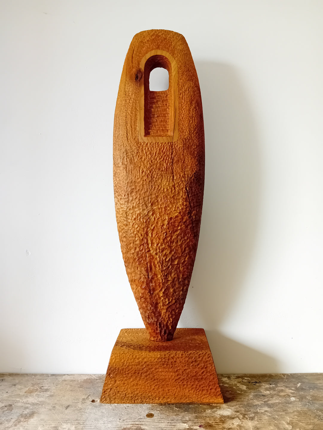 Nicola Beattie CAMINO sculpture — hand-carved cedar monolith with textured chisel-marked surface and arched window opening, symbolising a pilgrimage through life and a path towards hope. One-off original wooden artwork on cedar base.