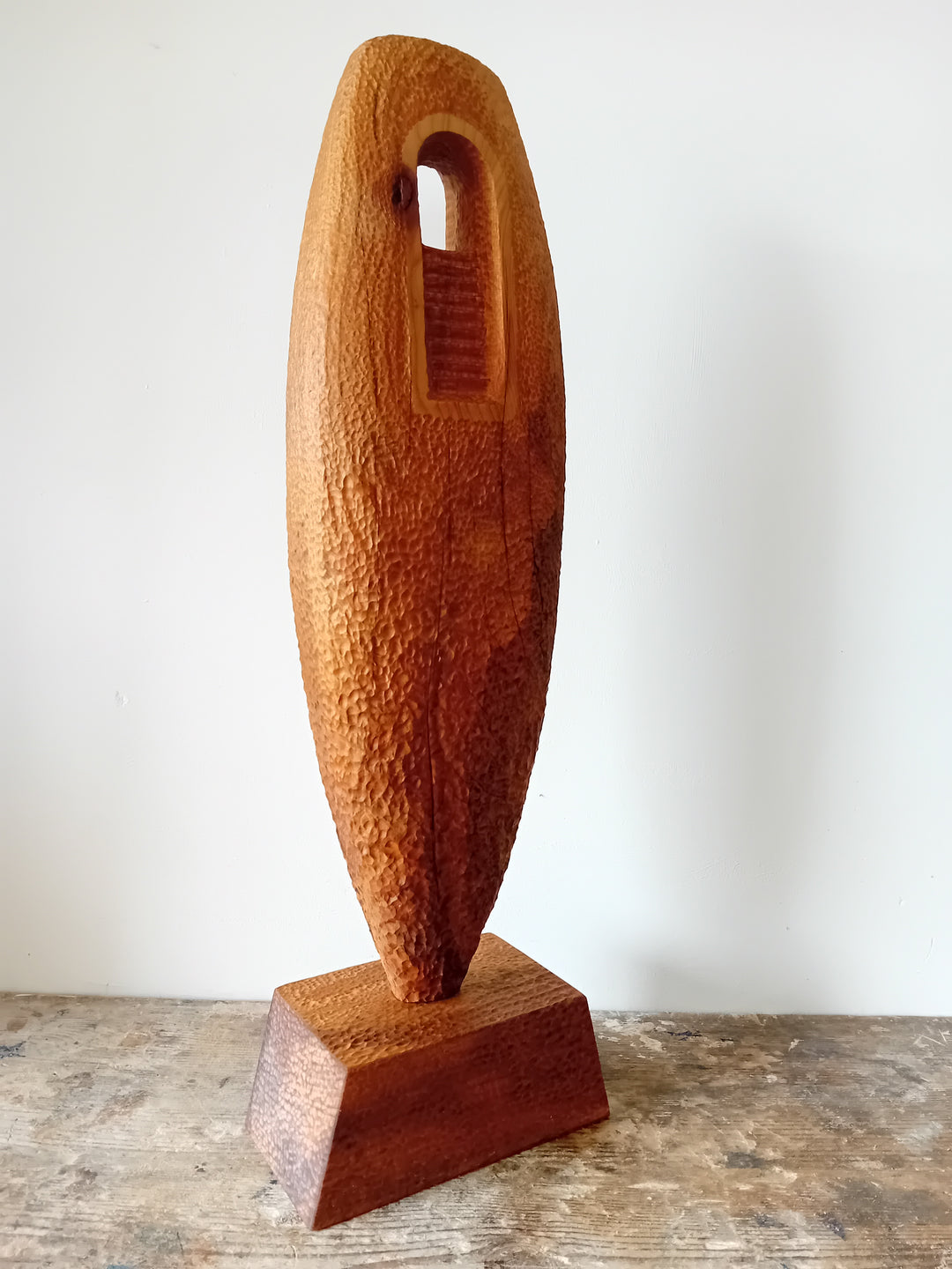 Nicola Beattie CAMINO sculpture — hand-carved cedar monolith with textured chisel-marked surface and arched window opening, symbolising a pilgrimage through life and a path towards hope. One-off original wooden artwork on cedar base.