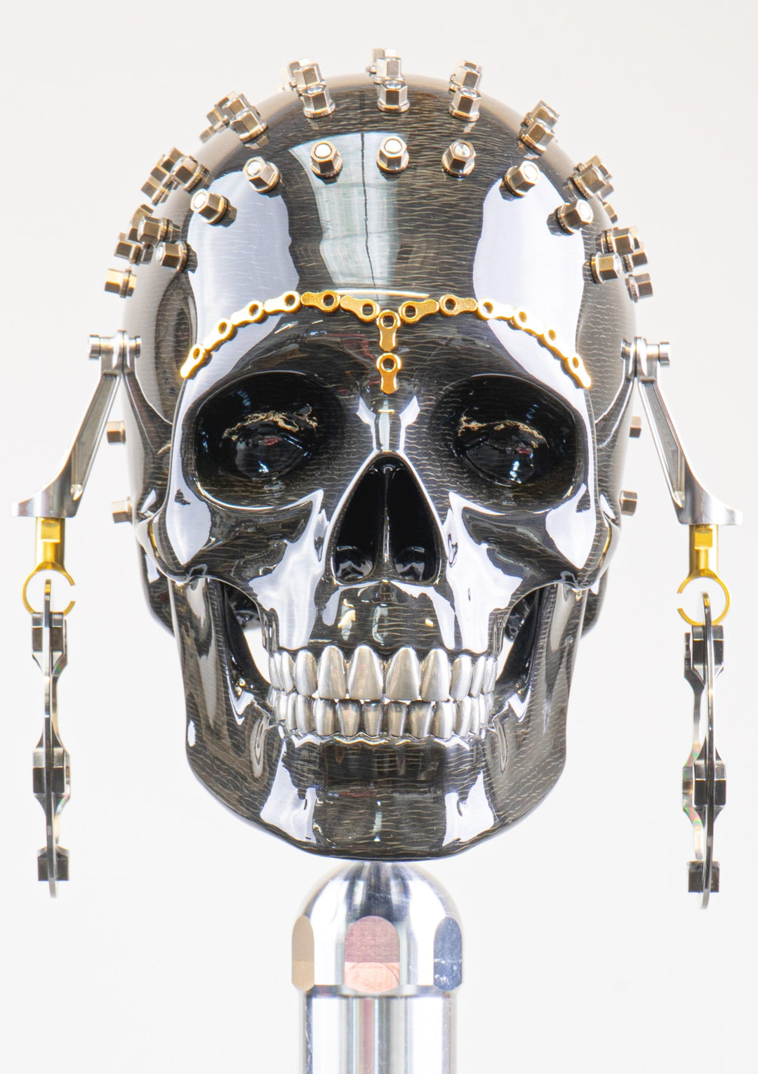 Alastair Gibson CarbonArt45 carbon fibre skull sculpture with high-gloss finish, Formula One components, stainless steel bolt crown detail, gold-plated accents and precision-engineered metal base