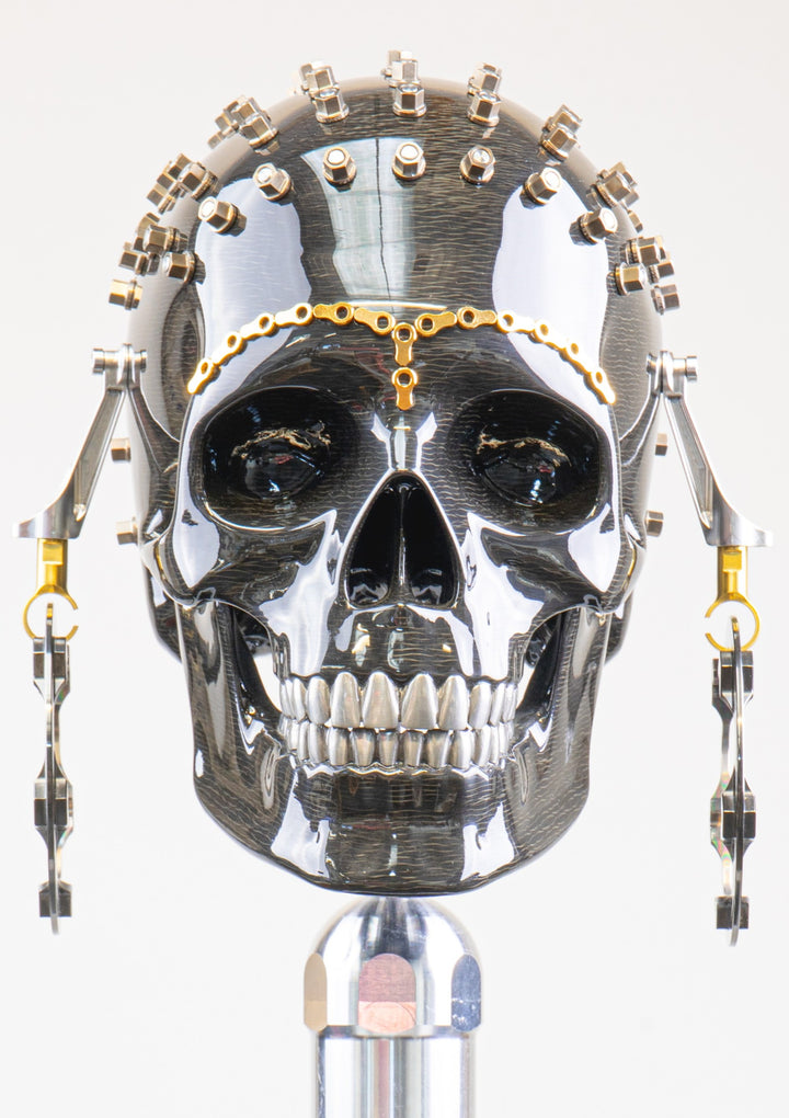 Alastair Gibson CarbonArt45 carbon fibre skull sculpture with high-gloss finish, Formula One components, stainless steel bolt crown detail, gold-plated accents and precision-engineered metal base