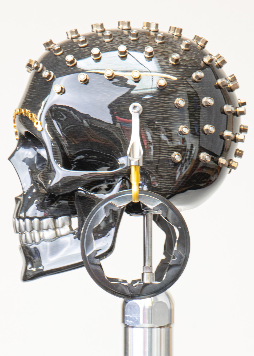 Alastair Gibson CarbonArt45 carbon fibre skull sculpture with high-gloss finish, Formula One components, stainless steel bolt crown detail, gold-plated accents and precision-engineered metal base