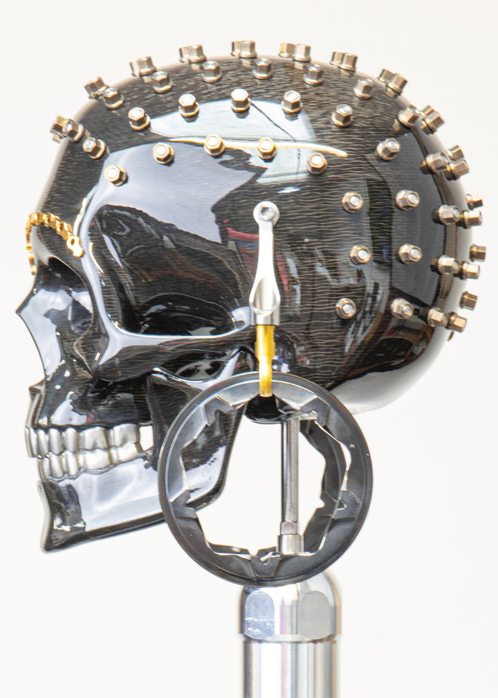 Alastair Gibson CarbonArt45 carbon fibre skull sculpture with high-gloss finish, Formula One components, stainless steel bolt crown detail, gold-plated accents and precision-engineered metal base