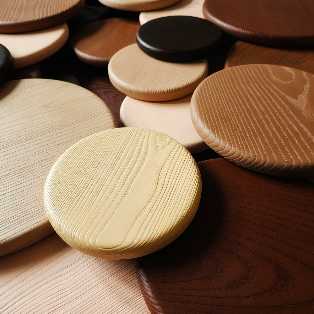 Wall sculpture made of layered wooden discs in various natural tones and wood grains, arranged in a circular cluster.
