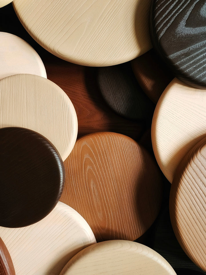 Wall sculpture made of layered wooden discs in various natural tones and wood grains, arranged in a circular cluster.
