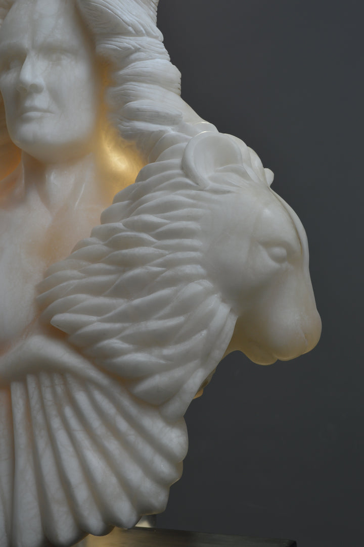 Deborah Harrison alabaster sculpture Cherubim, one-off hand-carved work in glowing white alabaster with translucent qualities, depicting a powerful male figure surrounded by symbolic forms including a goat-like animal, a bird, and a lion, mounted on slate, blending myth, spirituality, and masterful stone carving.