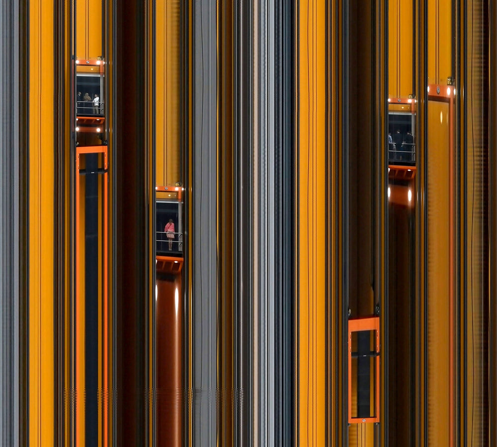 Richard P Jones City Climber #3, London fine art photographic print showing multiple glass elevators moving vertically through a modern architectural façade, created from reconstructed high-speed video imagery and printed as a giclée on brushed aluminium.