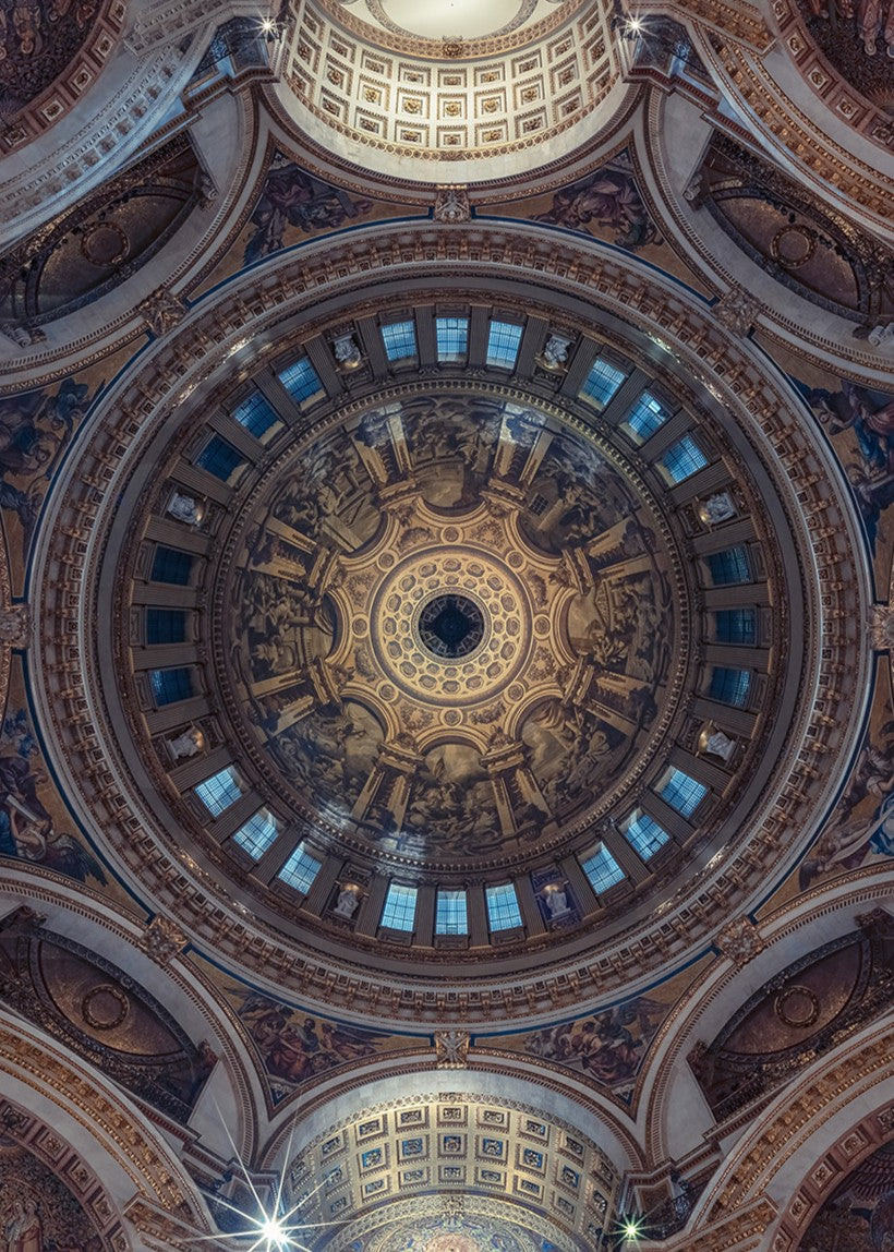 Panoramic photograph of St. Paul’s Cathedral interior, looking directly upward into the ornate dome designed by Sir Christopher Wren. The composition reveals gilded detailing, frescoes, marble arches, and the engineering mastery of the Whispering Gallery, captured in dramatic symmetry and ambient light.