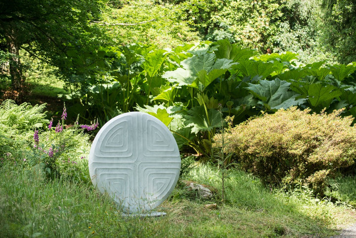 Contemplation V by Dominic Welch, a one-off Carrara marble sculpture with a circular form and four recessed triangular motifs, creating a harmonious, meditative design, currently exhibited at Ford Park Sculpture Garden.