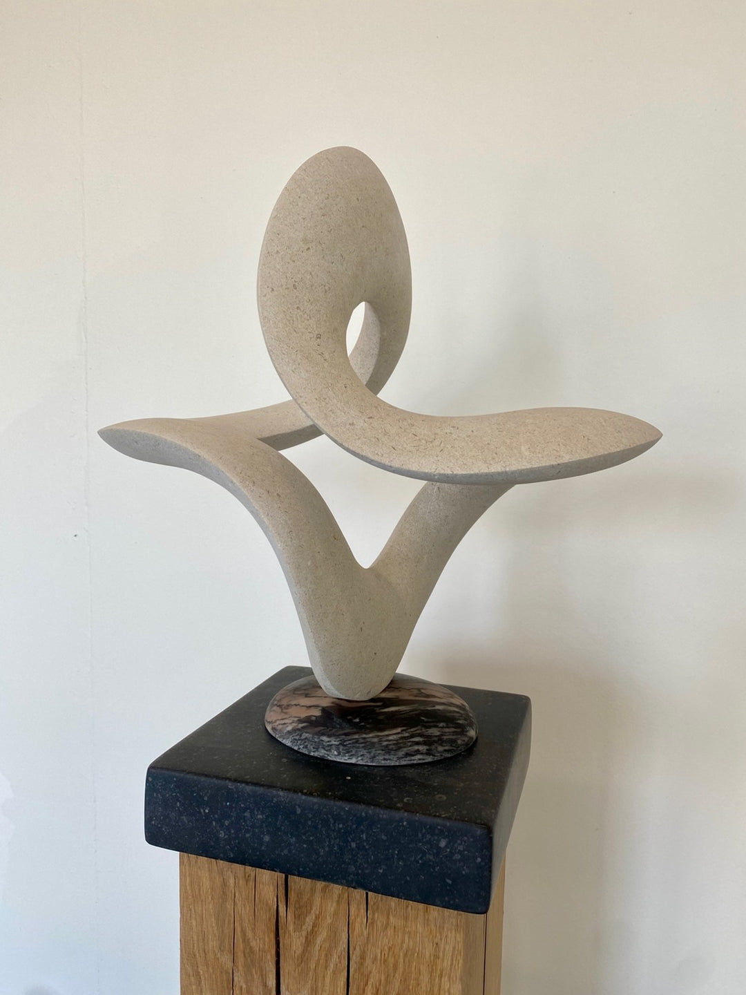 Abstract stone sculpture Cosmos 2025 by Hamish Holman, carved in pale Portland limestone with smooth organic curves and negative space, resting on a polished stone base, contemporary form.